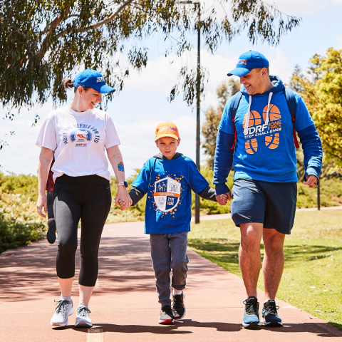 A smiling family walk together, hand in hand.