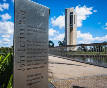 John Gordon Footbridge plaque with National Carillon and Aspen Island bridge in background.