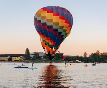 A colourful hot air balloon rises from the water of Lake Burley Griffin