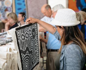 A woman examines a black and white painting at the AIATSIS indigenous art market.